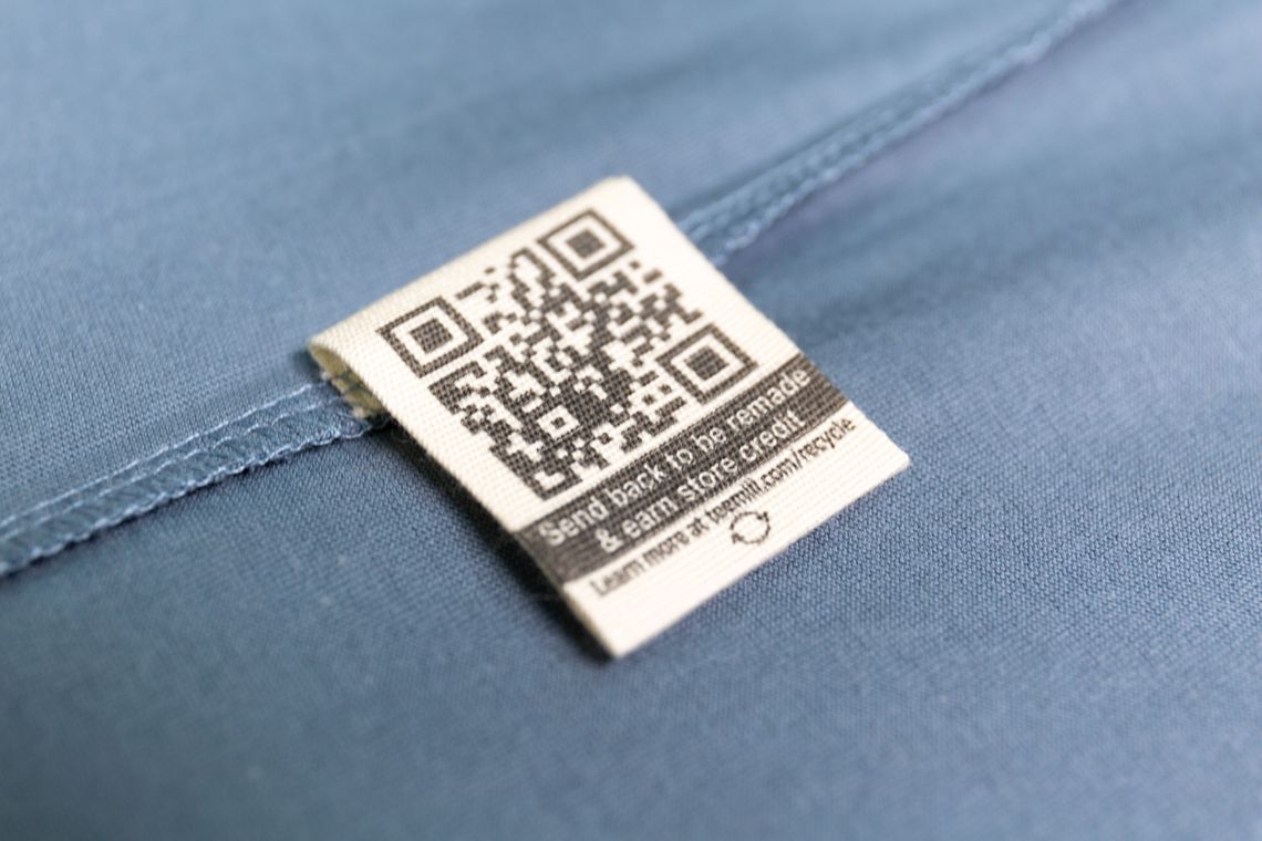 Close-up of a circular QR clothing remake tag on organic cotton fabric, emphasising circularity, sustainability, and UK musician streetwear identity