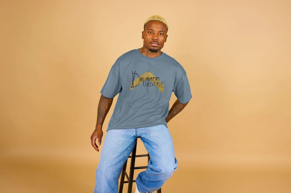 man wearing a premium oversized Above Average t shirt with the Drummers Universe logo on it